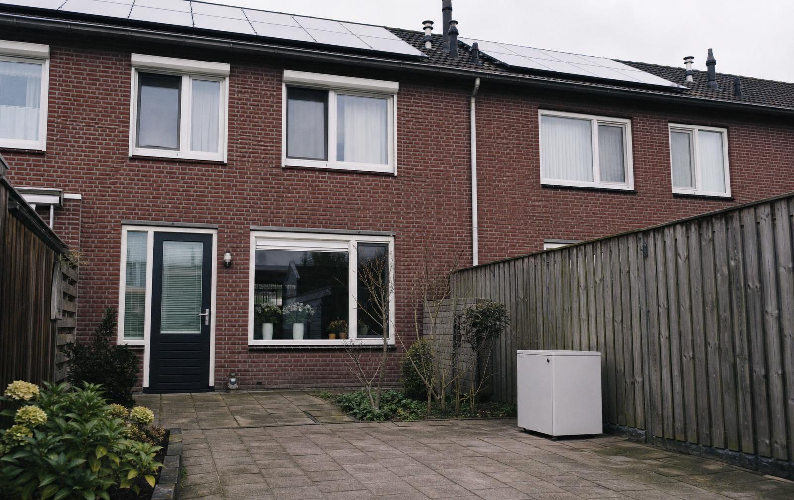 Achtertuin van een Nederlands rijtjeshuis met zonnepanelen op het dak en een thuisbatterij in een strak wit kastje